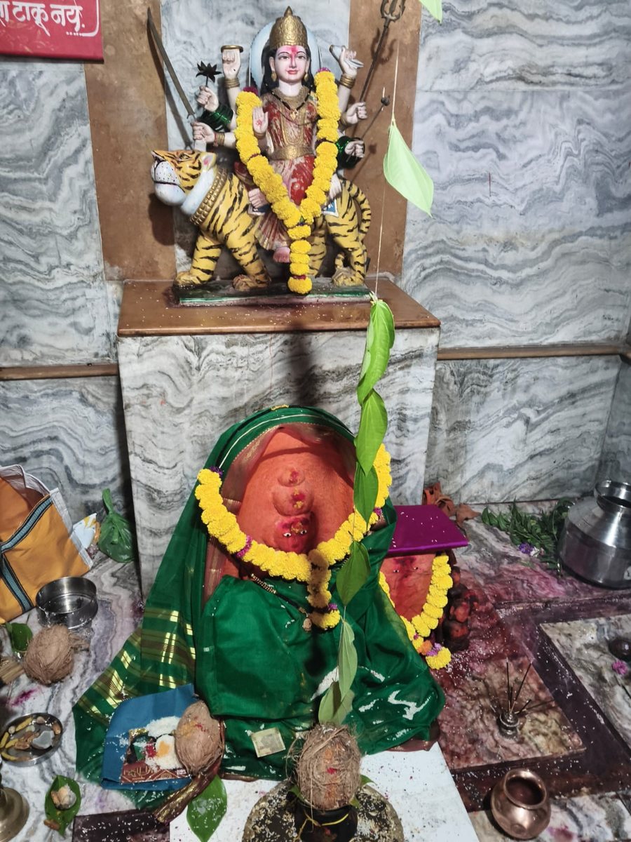 गाभाऱ्यातील श्री दुर्गा देवीची मूर्ती, झेंडूच्या फुलांचा हार आणि हिरवी साडी